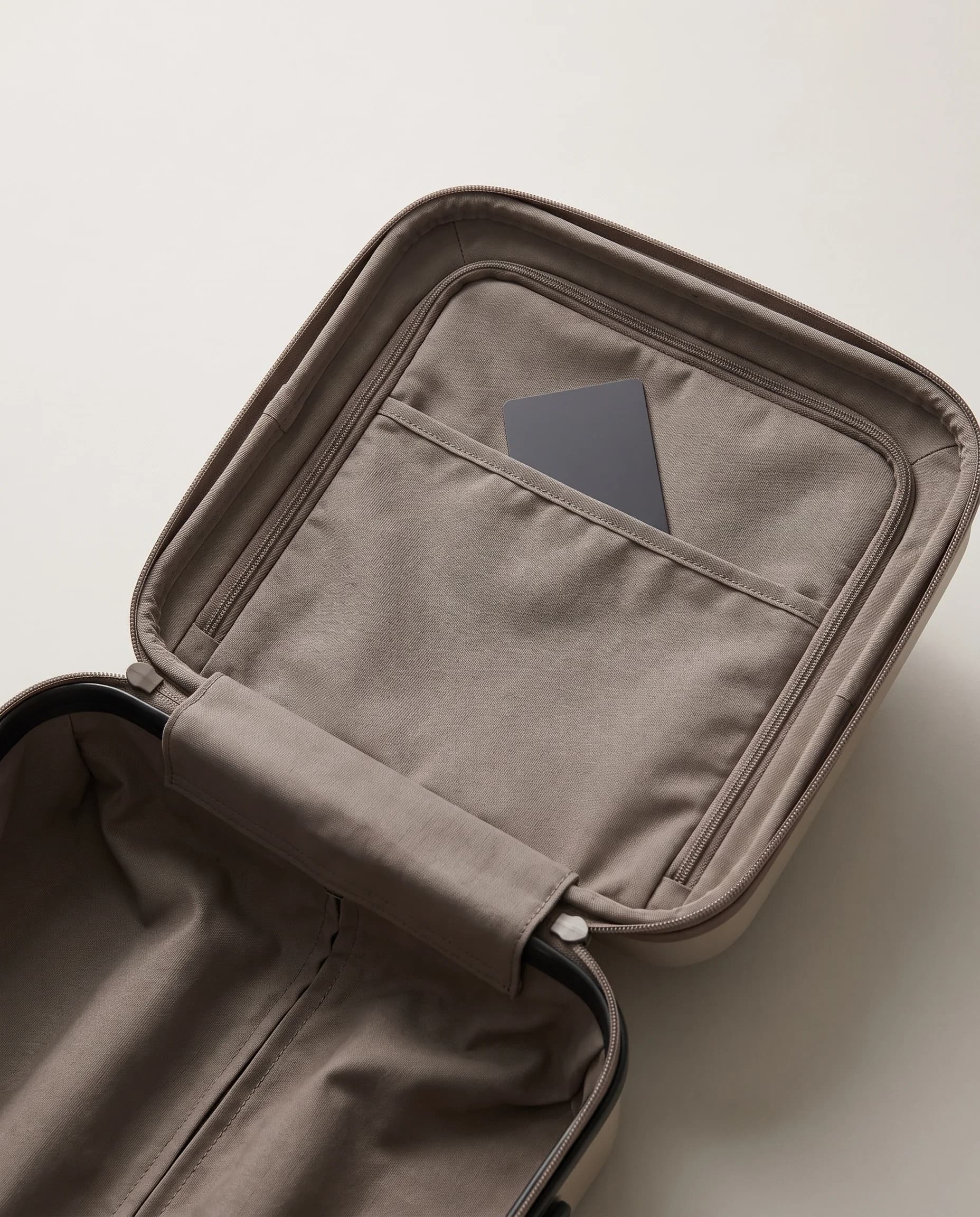 A blank graphite card in a plain warm-gray suitcase pocket.